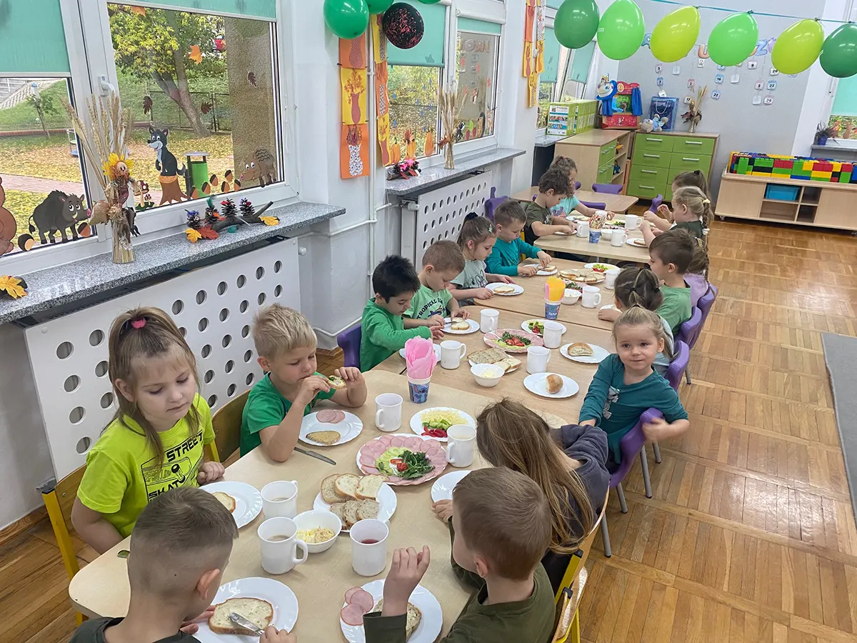  Dzieci siedzą przy stołac...